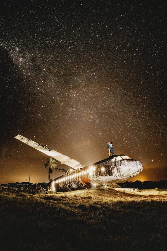 anonymous couple embracing on crashed plane with shiny lights